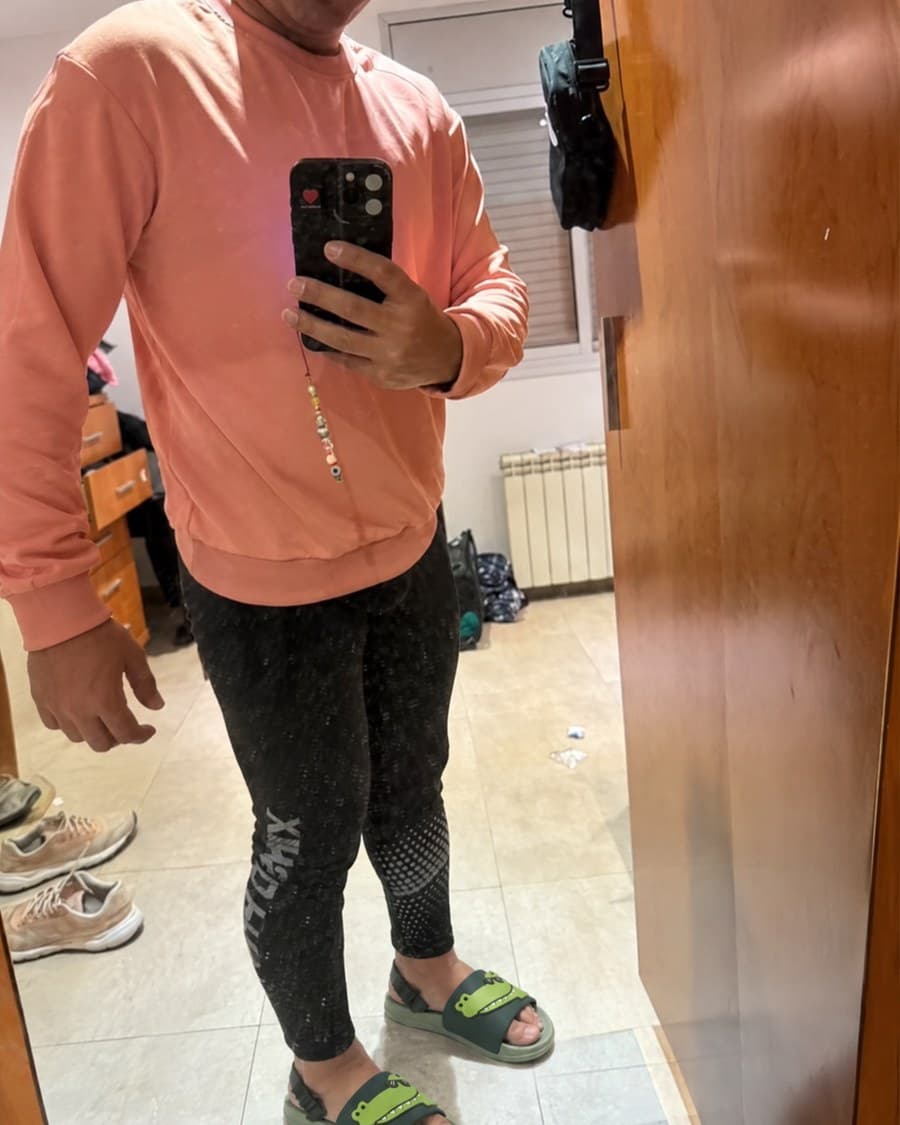 Les claquettes portées devant un miroir, avec un sweat corail et un legging noir.
